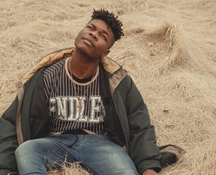 Singer Lani Rose seated on sandy shore